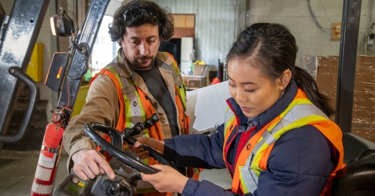 man and woman operating machinery at work